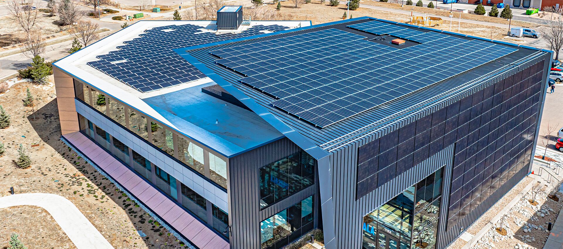 A commercial building with a vertical facade of solar arrays as well as two rooftop arrays