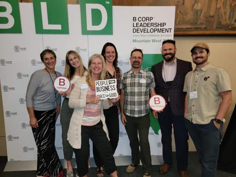 smiling people in front of b-corp leadership development sign