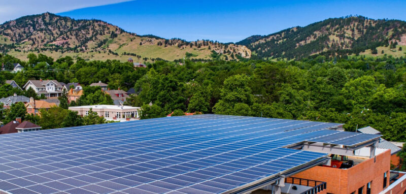 flat panel on building, mountains in the background, city of boulder