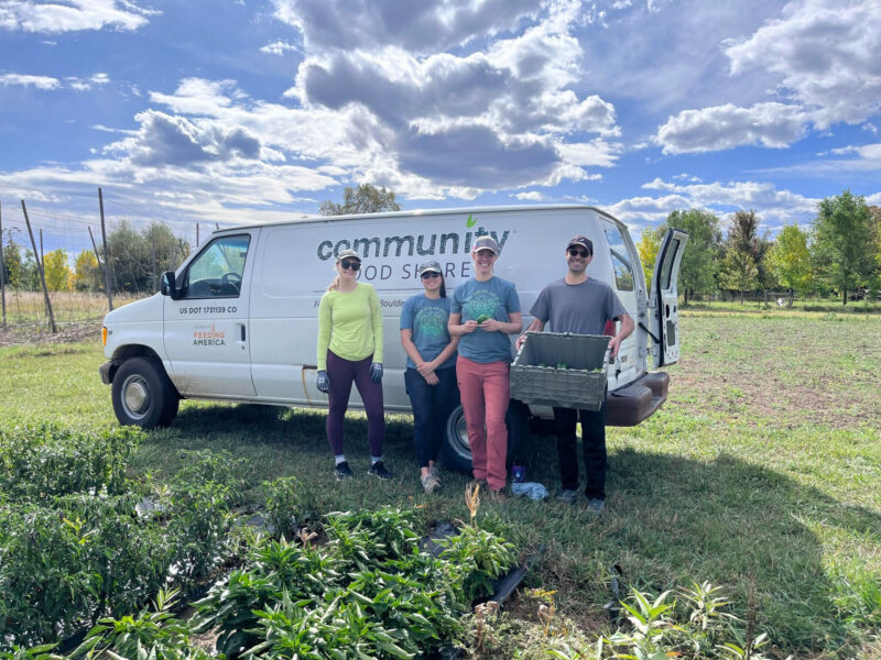 four smiling employees next to a truck with text: community food share