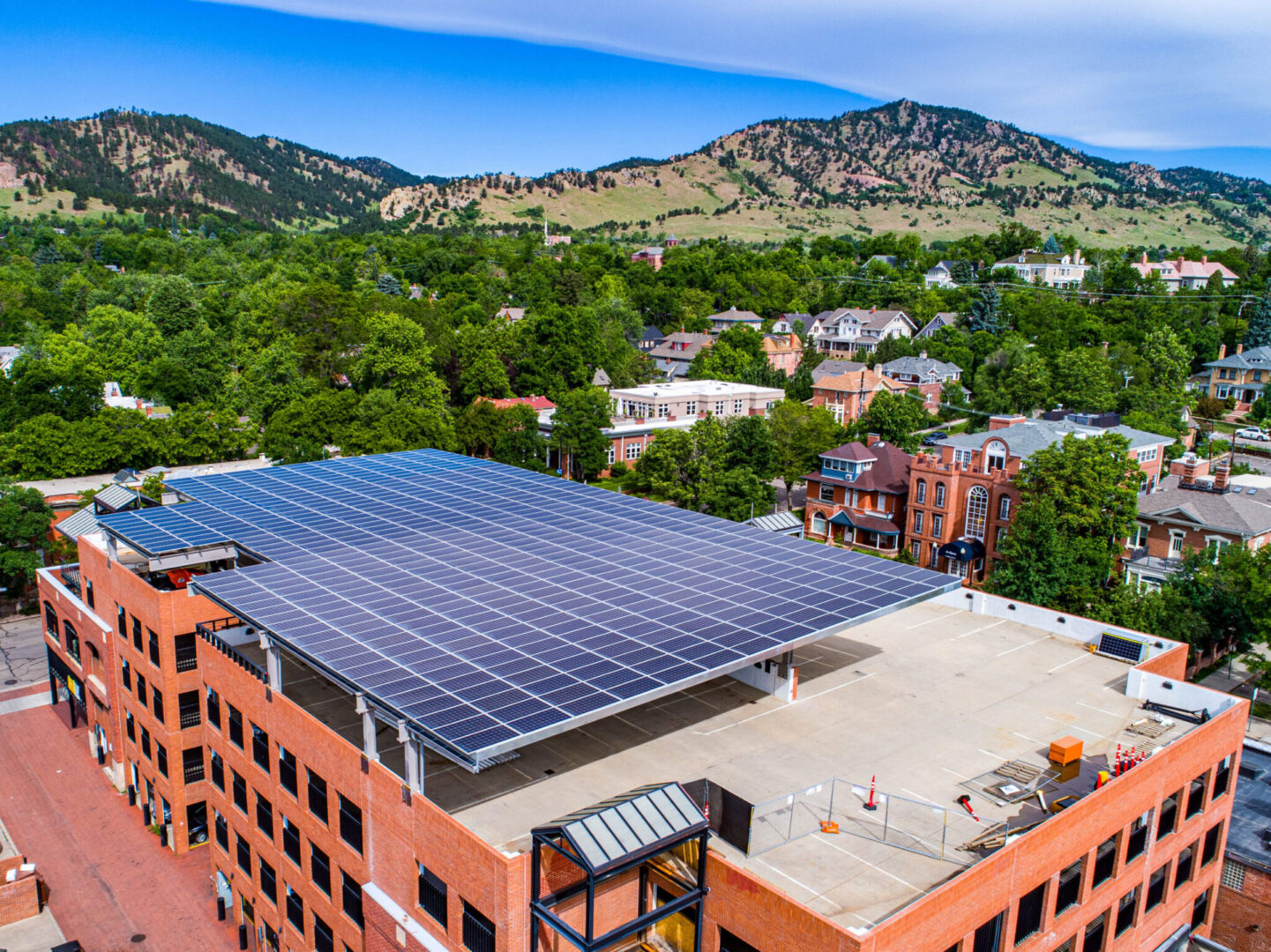 red brick building with solar panels on roof, mountains in the distance