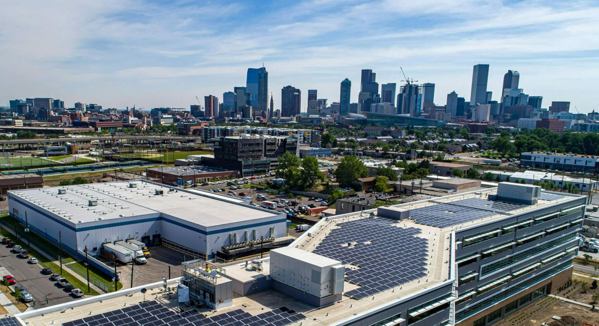 Downtown Denver background, solar panels on roofs foreground