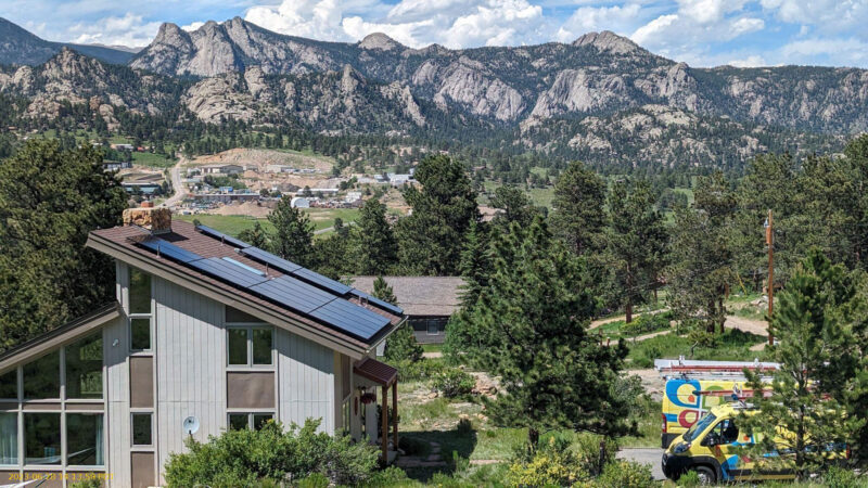 solar panels on diagonal roof with rocky mountain background