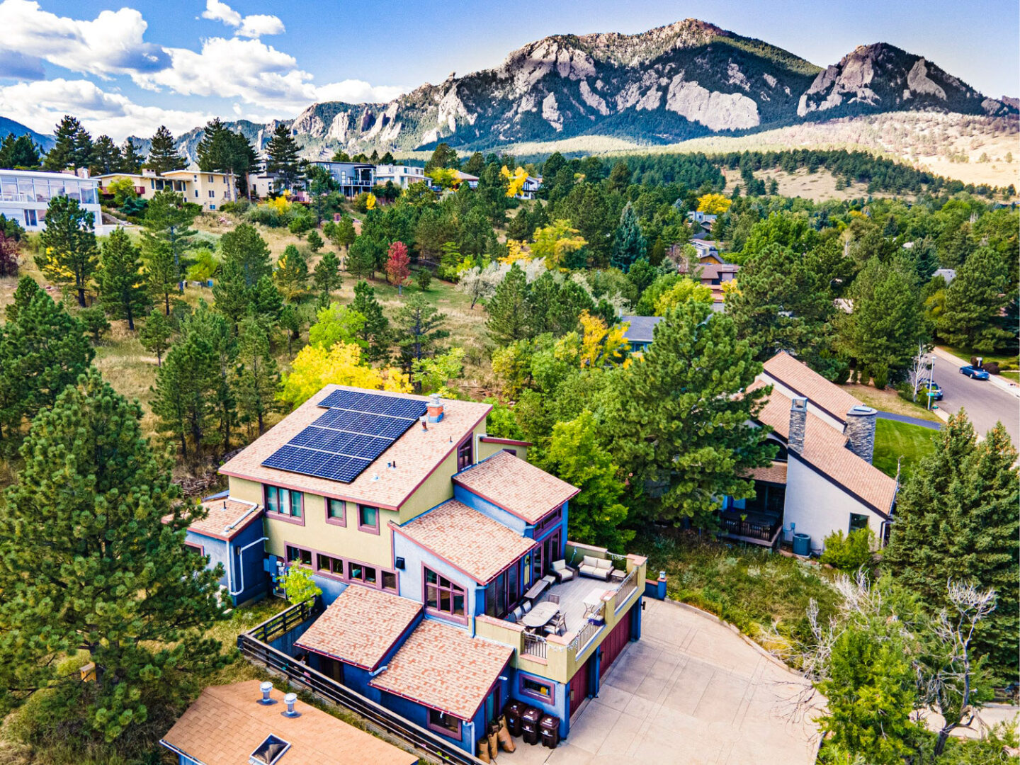 pink/orange home with solar panels, mountains in the distance