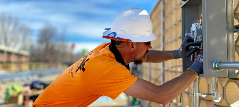 man in orange shirt working on electrical box