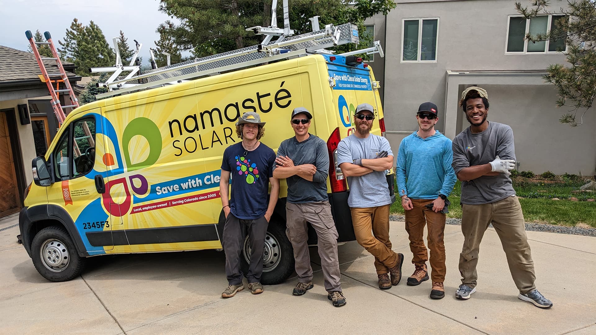 smiling employees around a namaste solar van