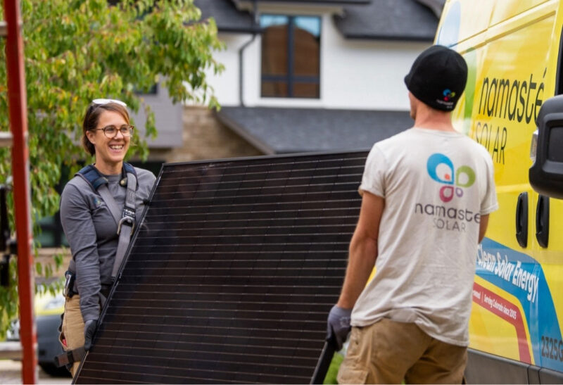 Two namaste solar employees carrying solar panel