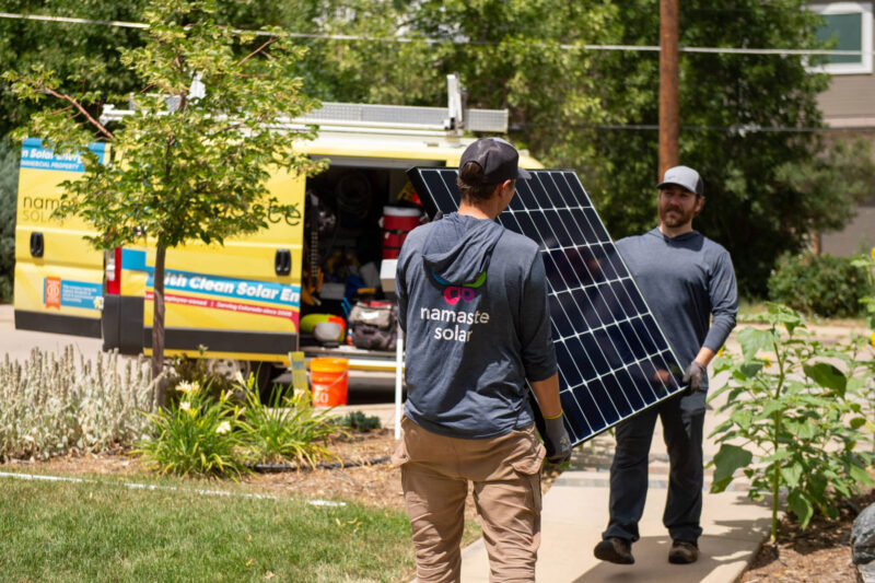 workers holding and walking with a solar panel