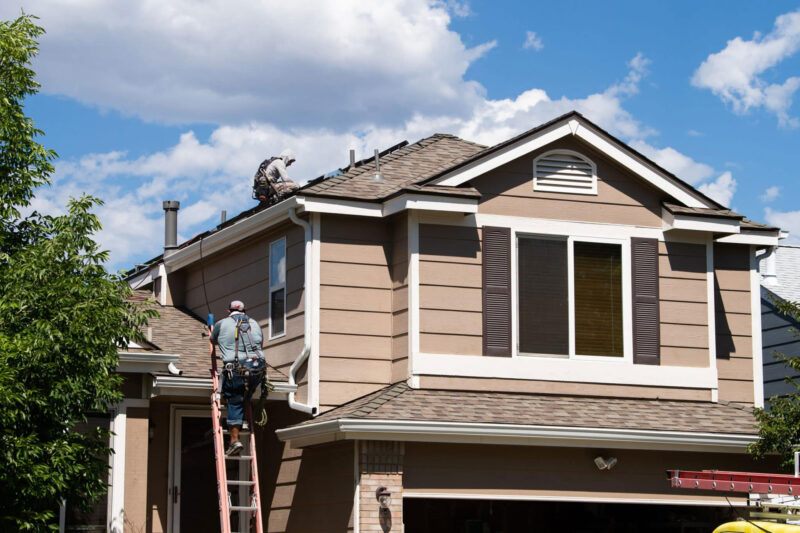 brown house with employees on ladder installing panels