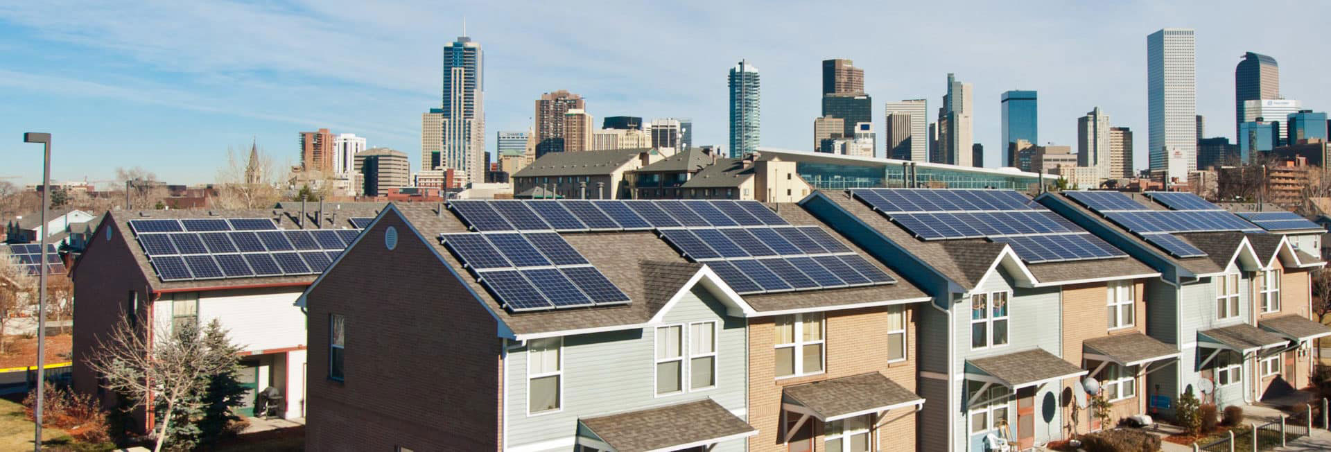 row of houses with solar panels, Denver skyline behind